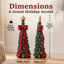 Winter dachshund statue wearing a knit hat, goggles, sweater, and scarf displayed among wrapped gifts and seasonal décor.
