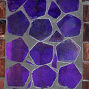 Close-up of the Modern Mosaic Fly-Through Bird Feeder in iridescent purple, showing irregular purple glass pieces with gray grout and brown mosaic border accents.
