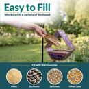 Modern Mosaic Fly-Through Bird Feeder in iridescent purple shown being filled with birdseed in a garden. Open design makes filling easy and works with millet, sunflower, safflower, and mixed seed.