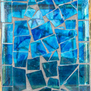 Close-up of the Modern Mosaic Fly-Through Bird Feeder in blue, showing irregular blue glass pieces arranged in a mosaic pattern with gray grout.