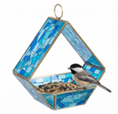 Modern Mosaic Fly-Through Bird Feeder in blue filled with birdseed, with a small black, white, and gray songbird perched on the edge of the open feeder.