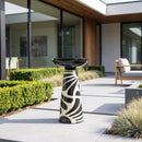 Black and cream decorative pedestal bird bath displayed on a modern outdoor patio, surrounded by landscaped greenery and contemporary seating.