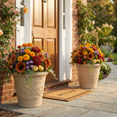 Two cream-colored decorative planters filled with colorful seasonal flowers, displayed beside a front door and walkway.