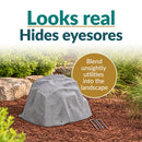 Gray artificial landscape rock with a realistic stone texture displayed in a landscaped garden with mulch, decorative stones, and greenery, designed to conceal unsightly outdoor utilities.