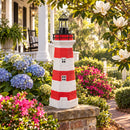 Red and white striped lighthouse statue displayed on a brick garden wall surrounded by blooming hydrangeas and pink flowers in a landscaped front yard.