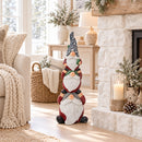 Stacked Christmas gnome statue displayed in a bright living room beside a fireplace and winter greenery.