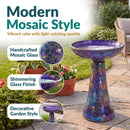 Crackled Glass Mosaic Bird Bath in iridescent purple shown outdoors on a patio, featuring handcrafted mosaic glass with a shimmering finish and vibrant purple, blue, and multicolor accents that catch the light.