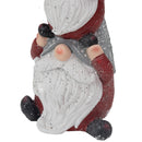 Close-up detail of the lower portion of a stacked Christmas gnome statue, showing a white textured beard, red clothing, gray hat, black shoes, and sparkling accents on a white background.