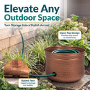 Copper Hammered Iron Hose Pot shown storing a coiled garden hose, featuring an open-top design for easy access and raised feet that support drainage and stability.